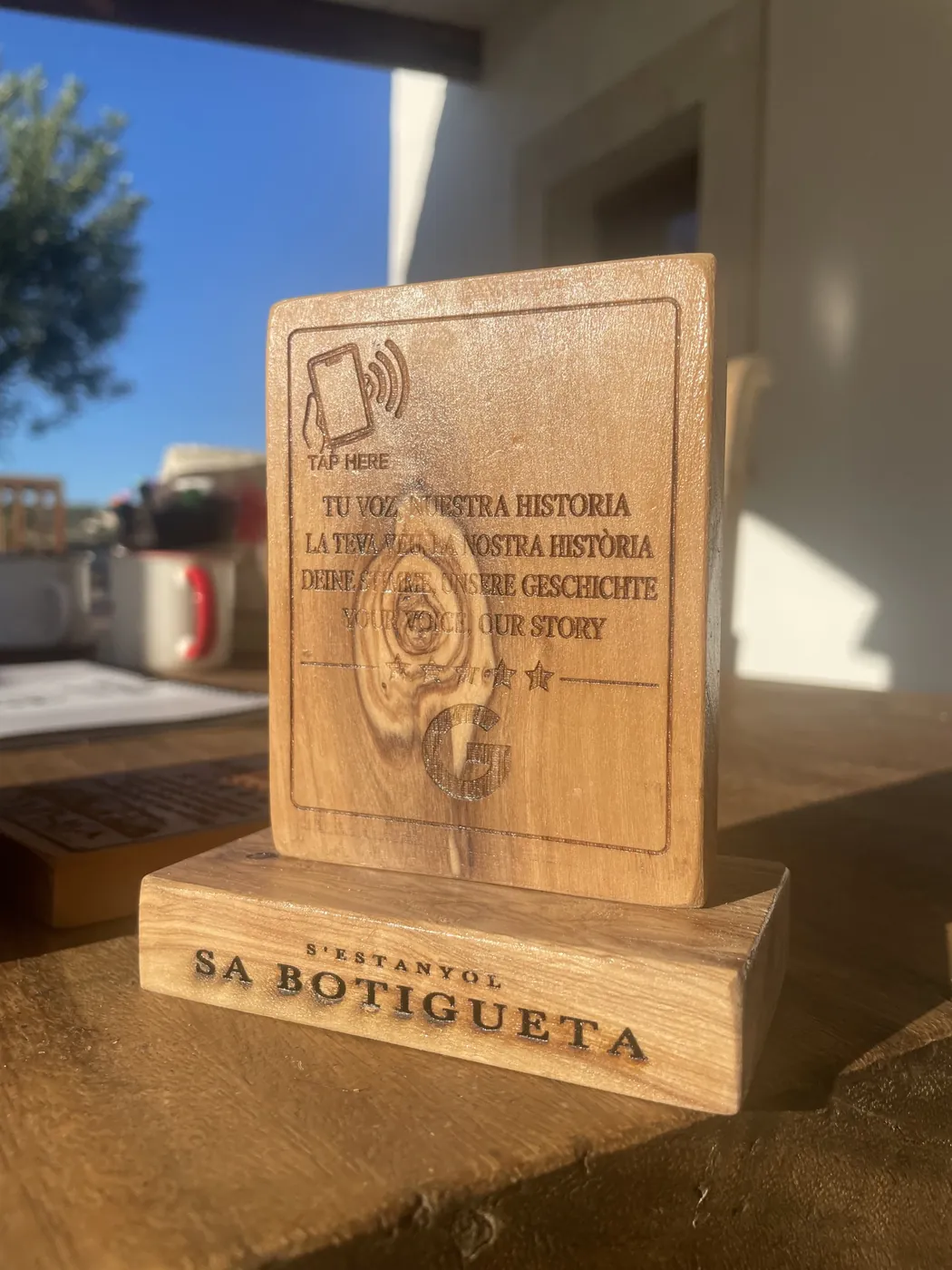 Placa de ullastre sobre su base, con el chip NFC y el icono de acercar el móvil